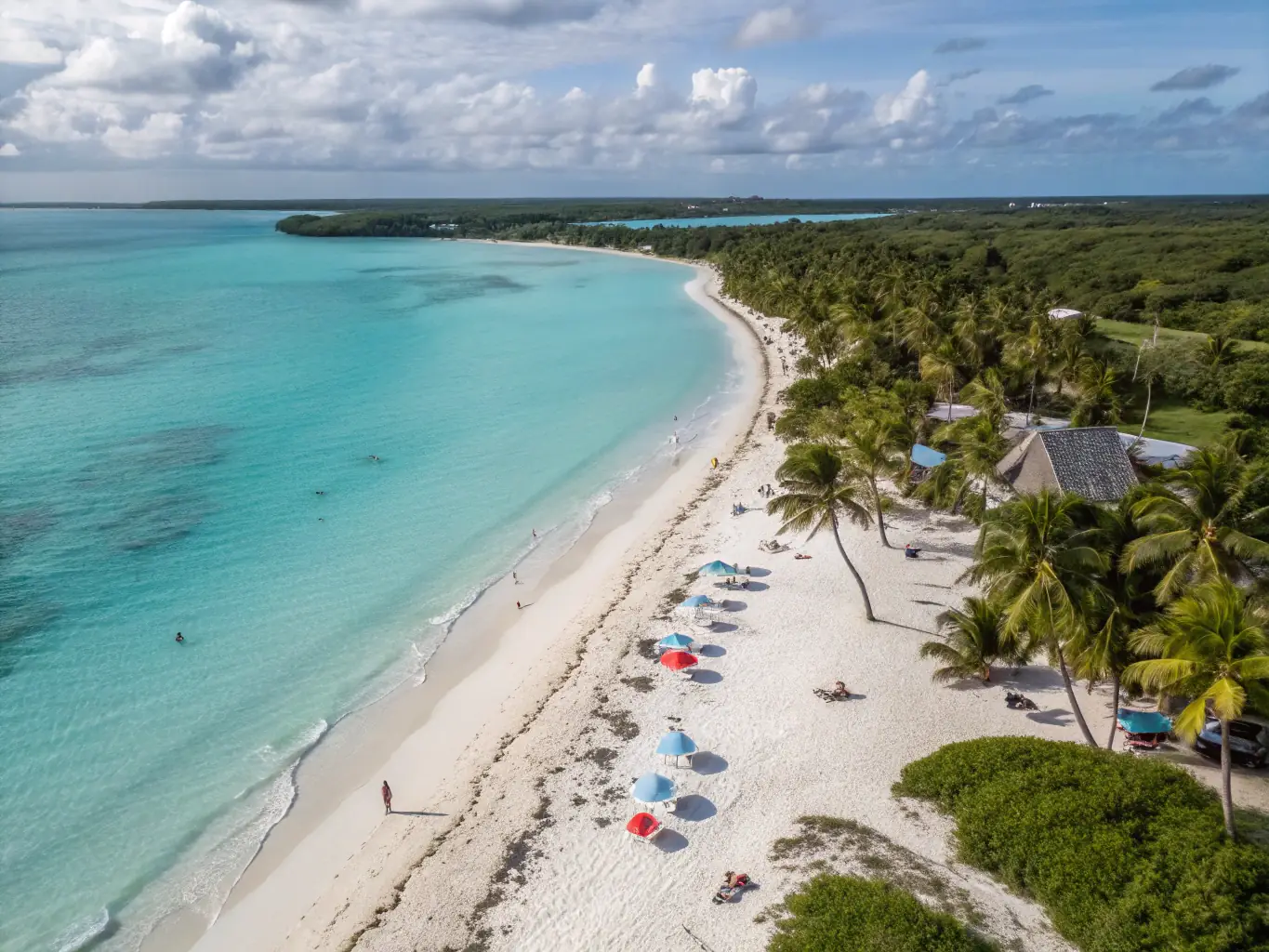 A stunning aerial view of a Caribbean island with crystal-clear turquoise waters, white sandy beaches, and lush green vegetation.